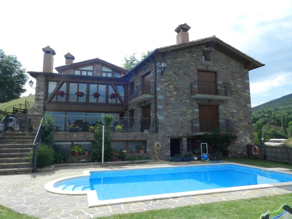 une maison avec une piscine en face de celle-ci dans l'établissement Apartaments El Tossalet, à Bonansa