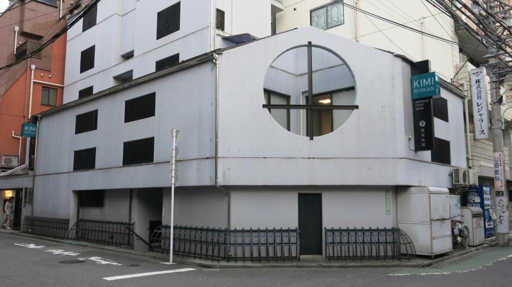 a white building with a round window on a street at Kimi Ryokan in Tokyo