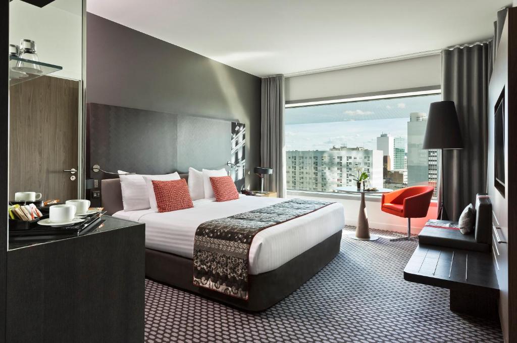 a hotel room with a bed and a large window at Melia Paris La Defense in Courbevoie