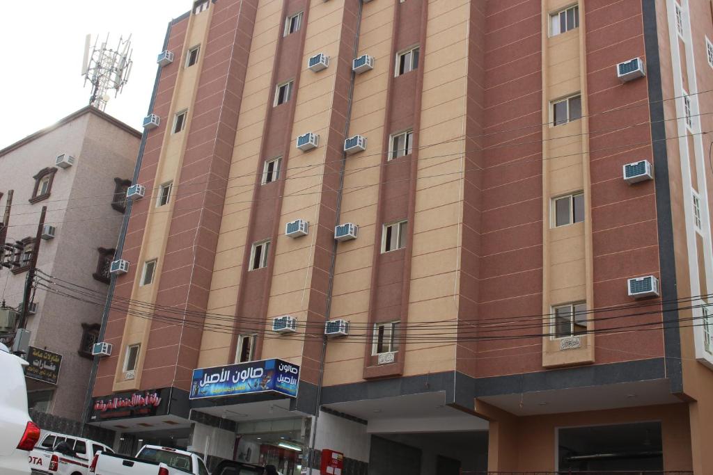 un edificio alto con coches estacionados frente a él en Rayanat Abha Aparthotel, en Abha