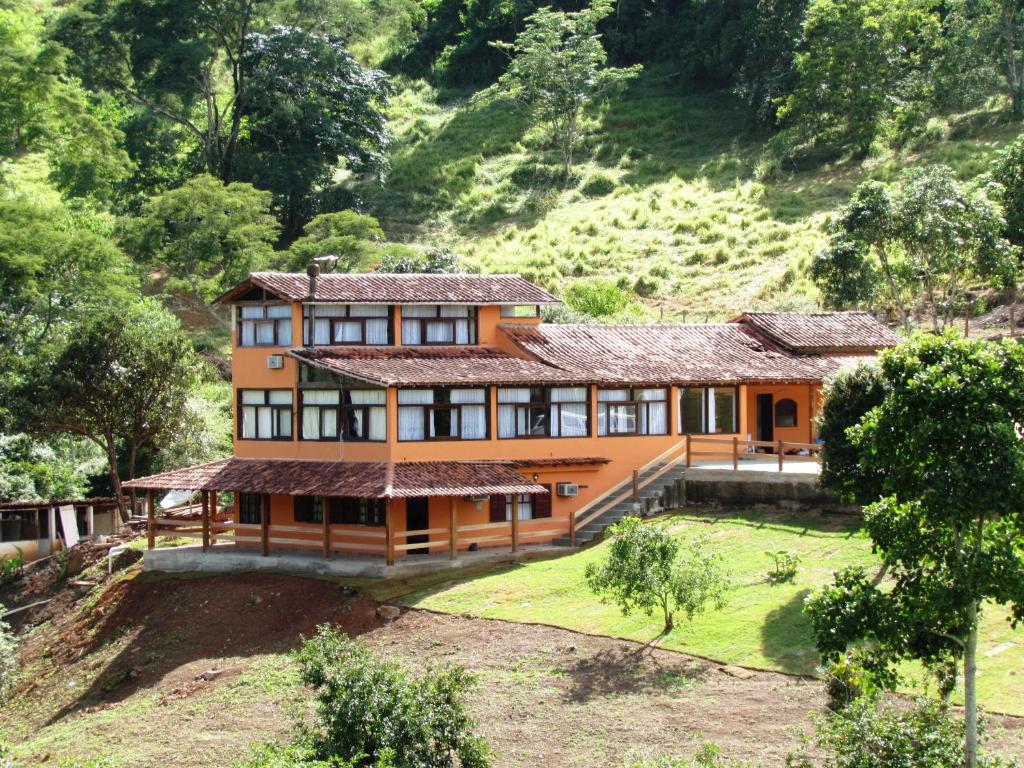 an orange house with a hill in the background at Hotel dos Bretões in Sapucaia