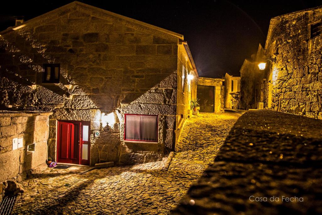 un antiguo edificio de piedra con puertas rojas por la noche en Casa da Fecha, en Parada
