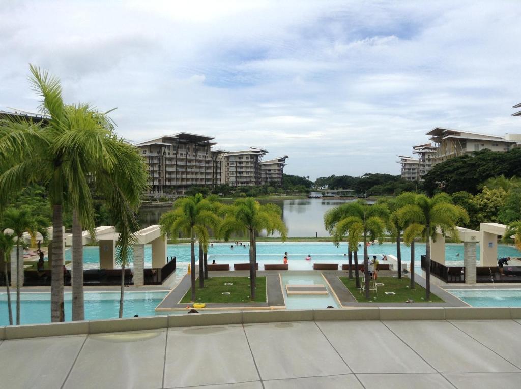 a view of the pool at the resort with palm trees at Pico Beach Front Condo in Nasugbu