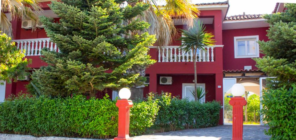a red house with two red parking meters in front of it at No Name Apartments in Laganas