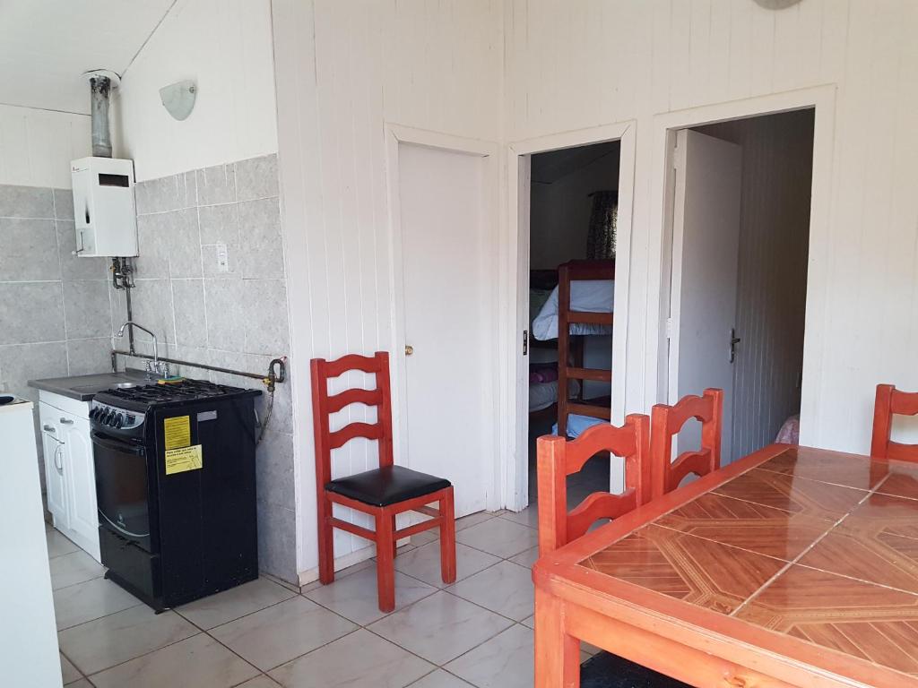 a kitchen with a table and a chair and a stove at Turismo el Bosque in Pichilemu