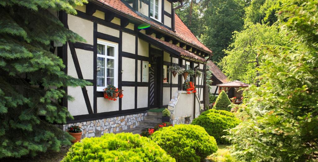 a black and white house with flowers in a garden at U Beaty in Ruciane-Nida