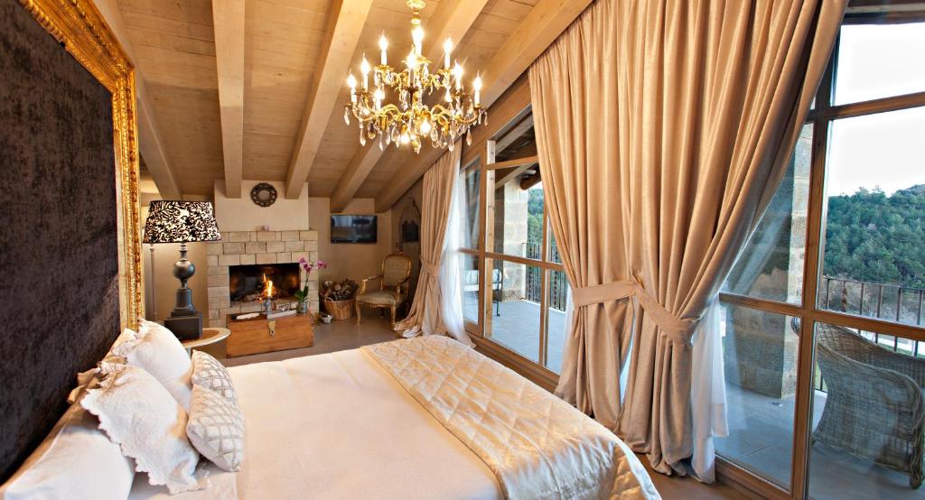 a bedroom with a bed and a fireplace and a chandelier at La Vella Farga Hotel in Lladurs