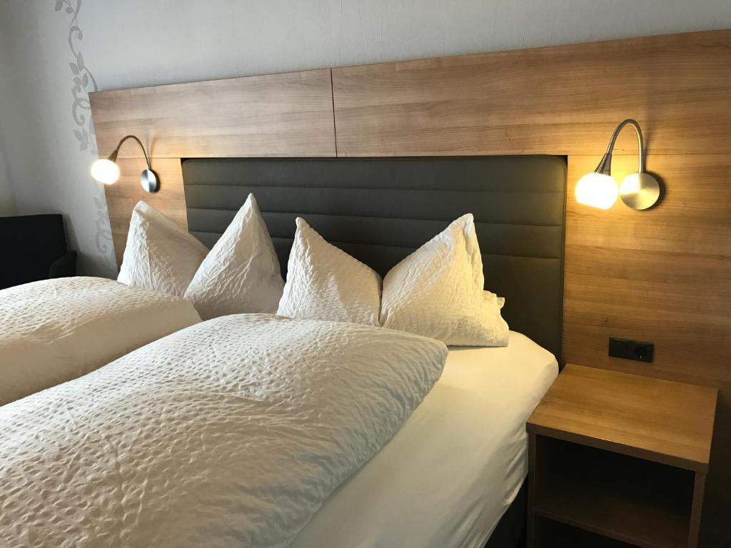 Schlafzimmer mit einem Bett mit weißer Bettwäsche und Kissen in der Unterkunft Gasthof zum See in Wiesensteig
