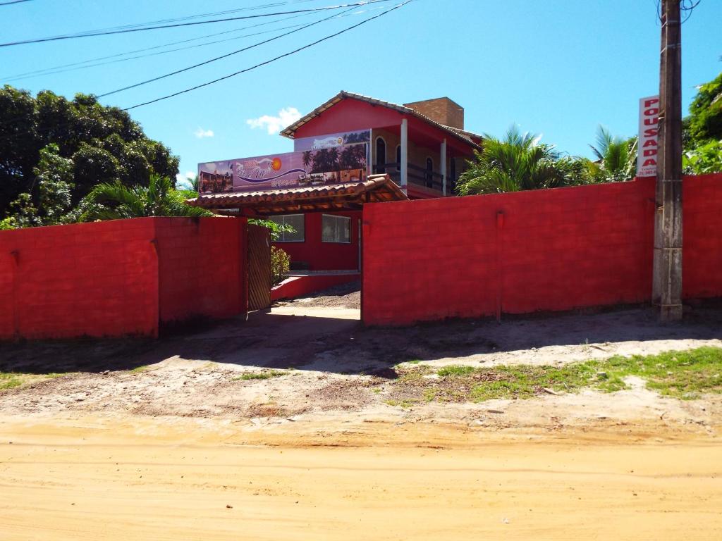 a house with a red fence and a red wall at Pousada Rio e Mar in Massarandupio