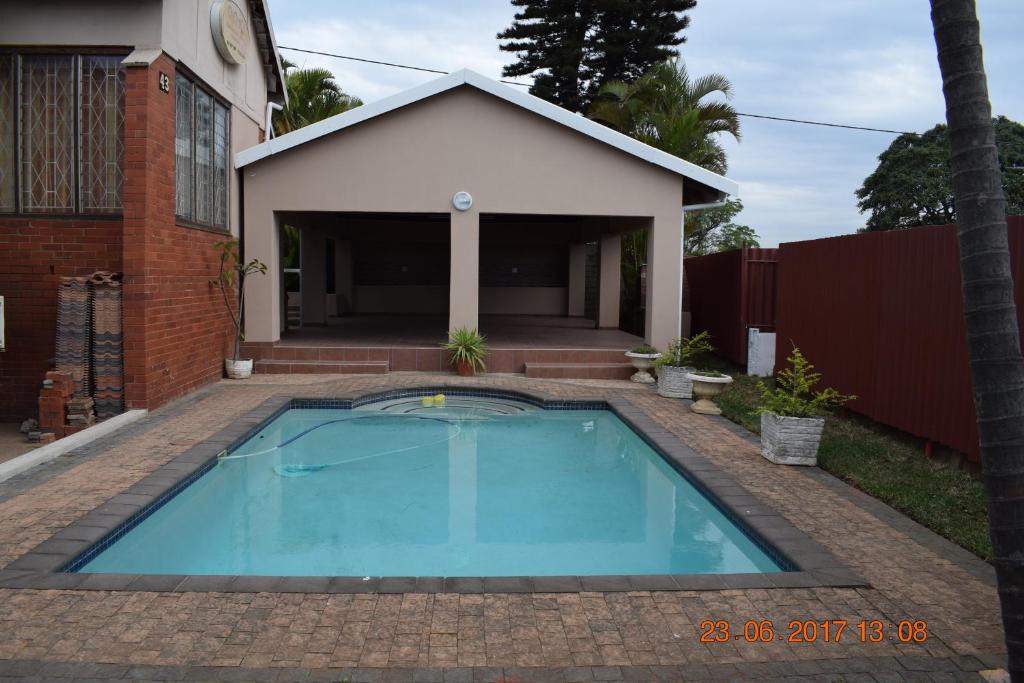 a swimming pool in front of a house at Clycherco Self Catering in Durban