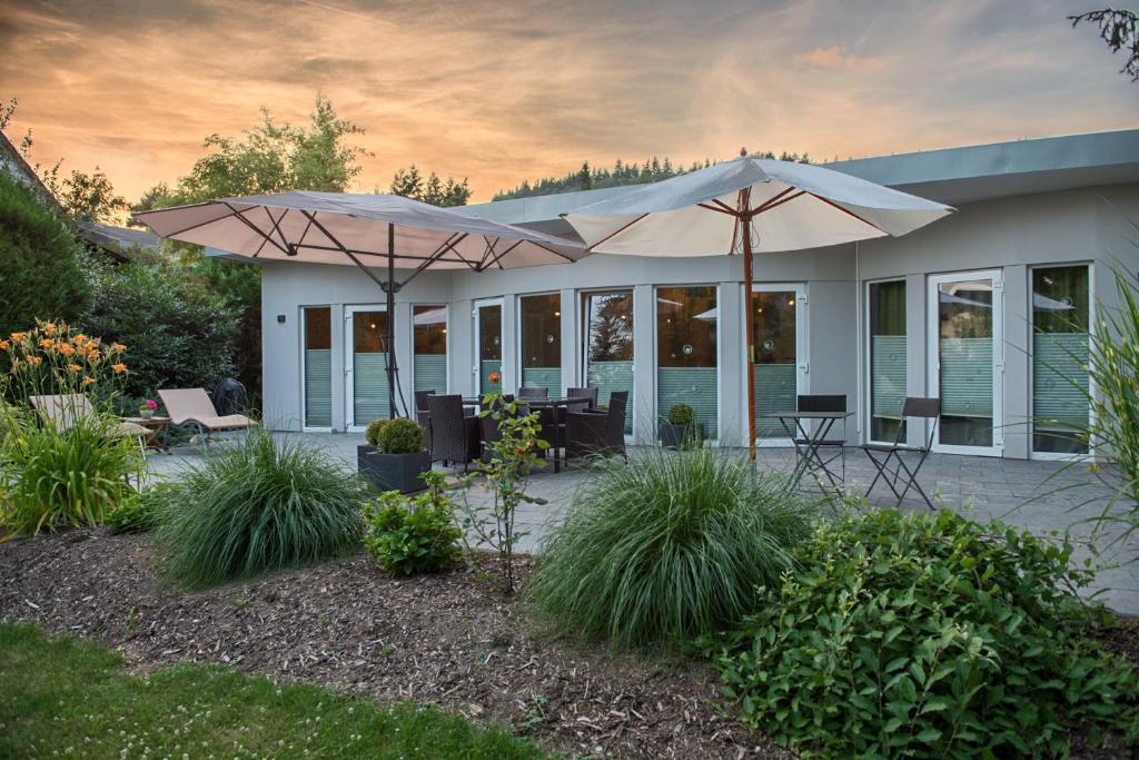 een patio met 2 parasols in een tuin bij relactive-mosel Feriendomizil in Traben-Trarbach