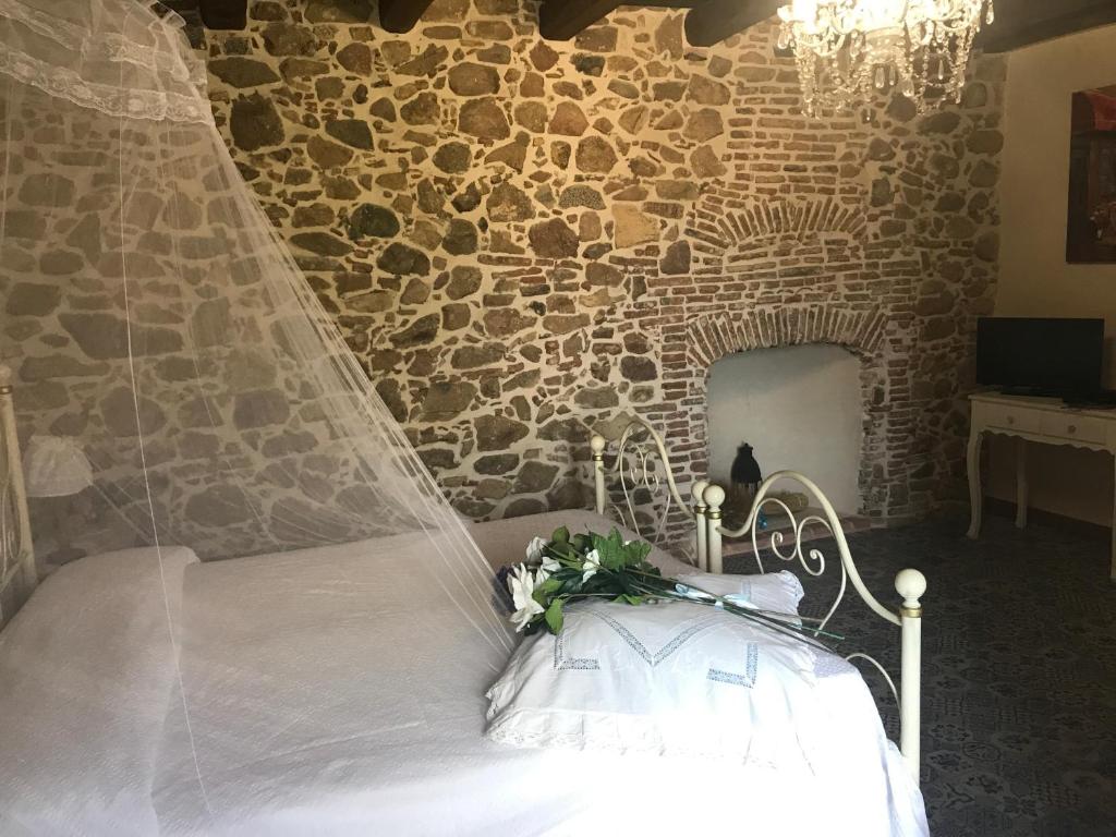 uma cama de casamento com um véu num quarto com uma parede de pedra em Vesta em Sorgono