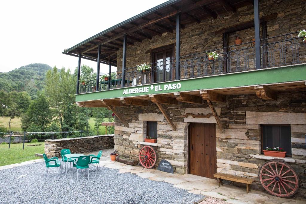 um edifício com uma varanda, uma mesa e cadeiras em Albergue El Paso em Vega de Valcarce