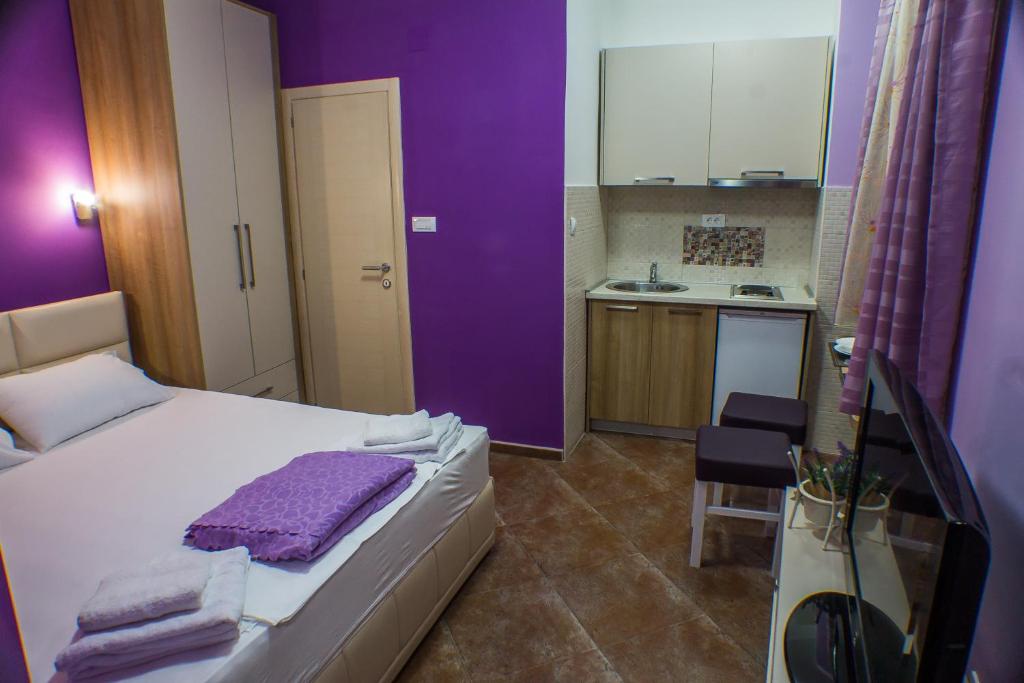 ein Schlafzimmer mit lilafarbenen Wänden, einem Bett und einer Küche in der Unterkunft Apartments Casa del Sol Jovana in Kotor