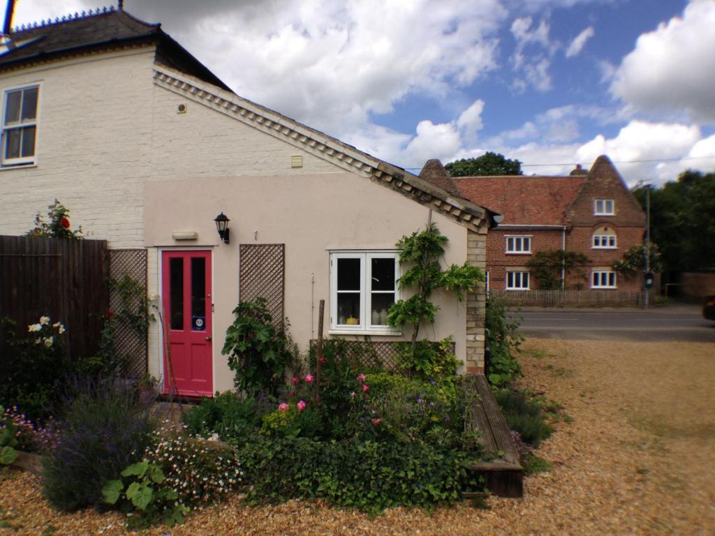 een wit huis met een rode deur in een tuin bij Over Studio Apartment in Over