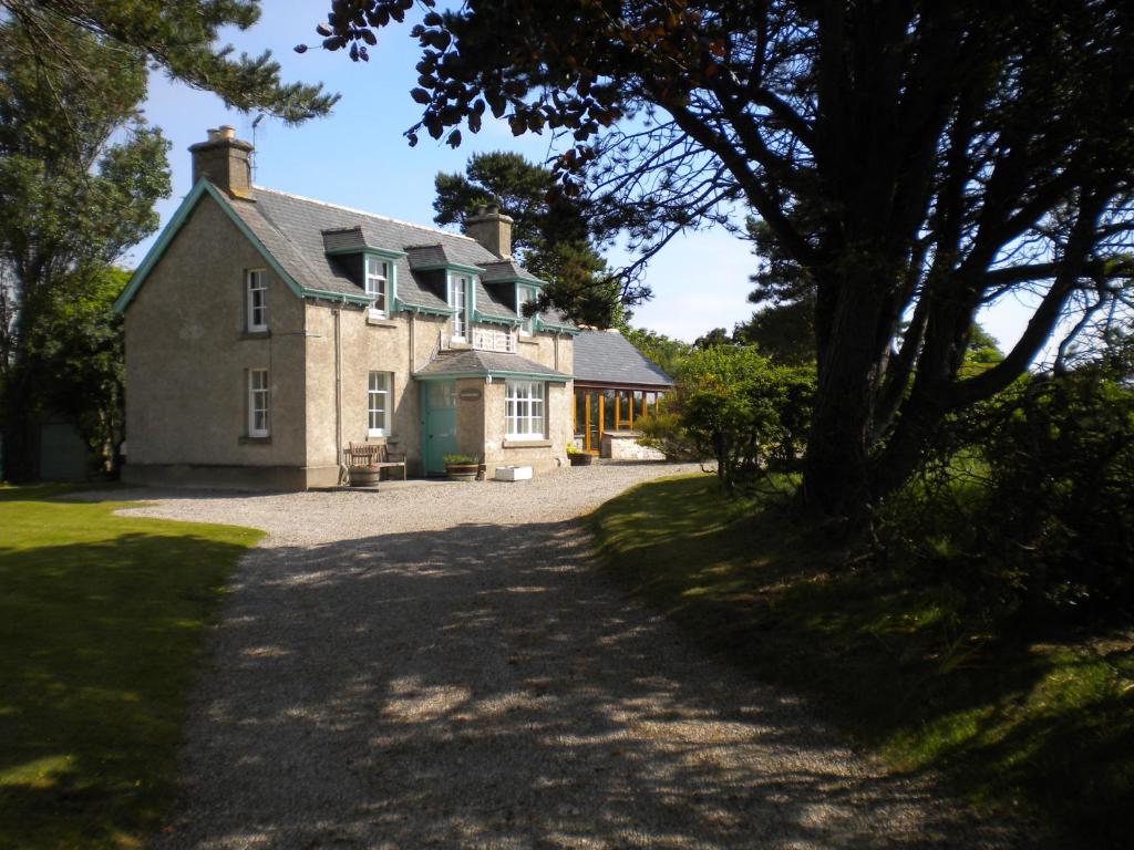 a large house with a driveway in front of it at Auchencairn Cottage in Brora