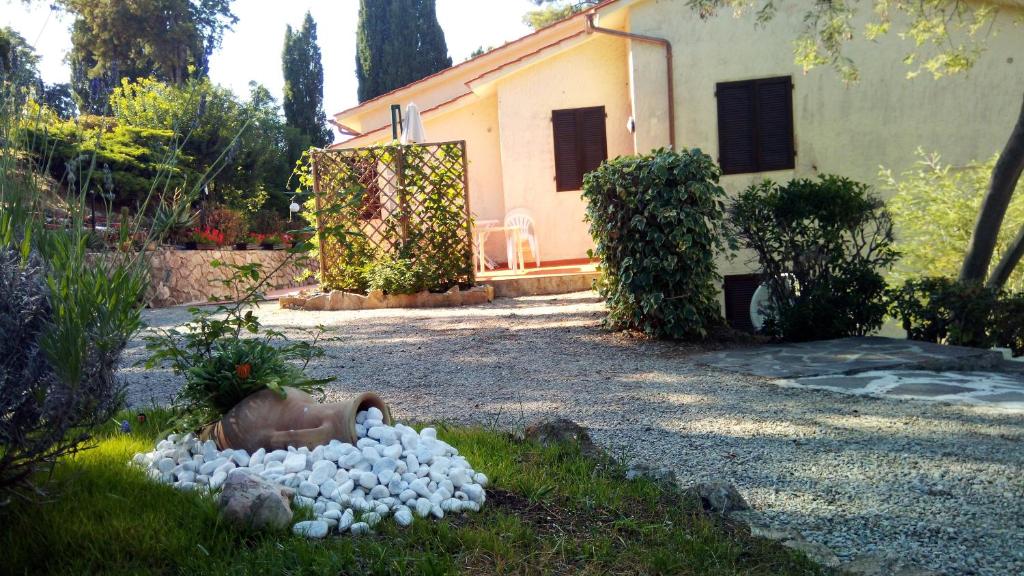 a garden with a house and a bunch of rocks at Residence Le Mimose in Procchio