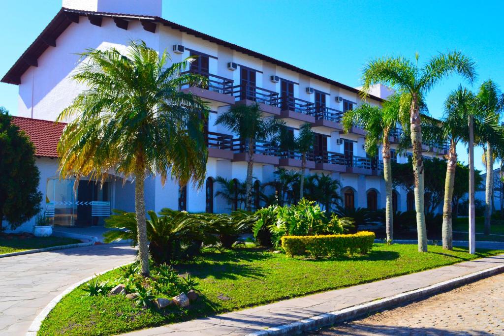 a building with palm trees in front of it at Hotel das Figueiras in São Lourenço do Sul