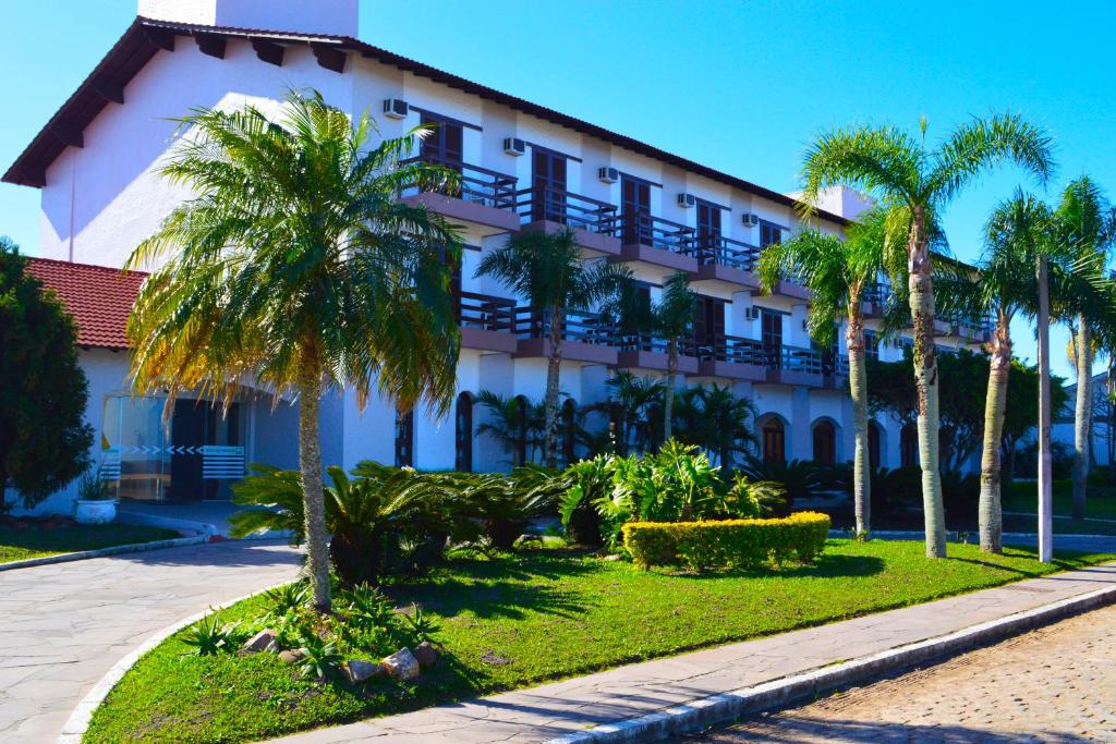 un edificio con palmeras delante en Hotel das Figueiras, en São Lourenço do Sul