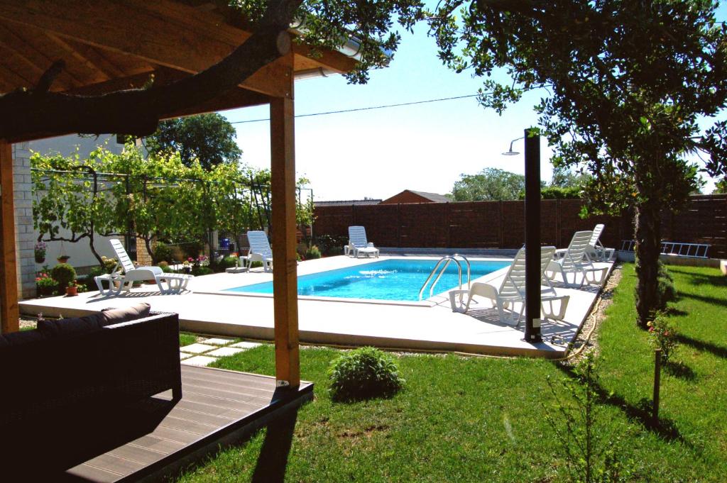 a swimming pool with a bunch of chairs around it at Filipovic Apartments with Pool in Biograd na Moru