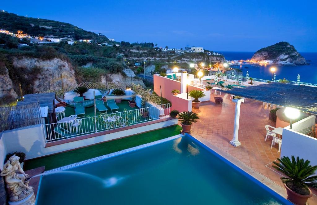 a pool with a view of the ocean at night at Hotel Residence S.Angelo in Ischia