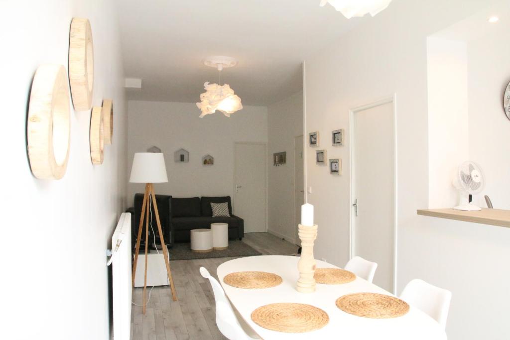 a white dining room with a white table and chairs at A & V Appart'hôtel in Lille