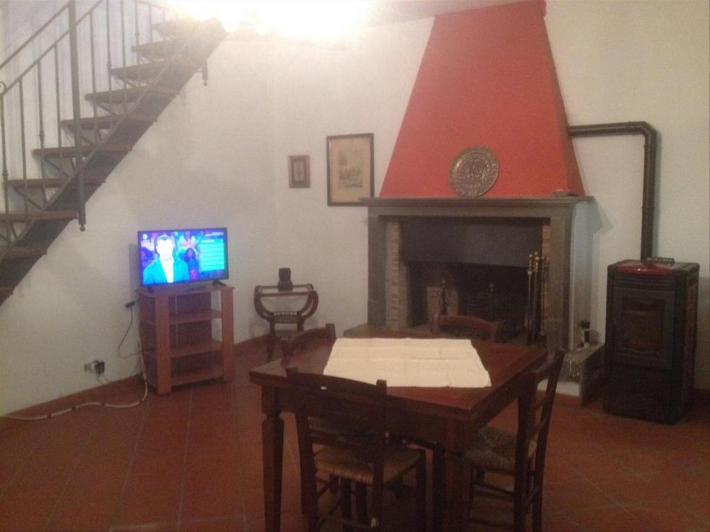 ボルゴ・ア・モッツァーノにあるCasa di Anchianoのリビングルーム(テーブル、テレビ、暖炉付)