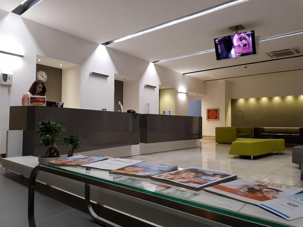 kobieta stojąca w holu ze szklanym blatem w obiekcie Hotel Artemide w mieście Aversa