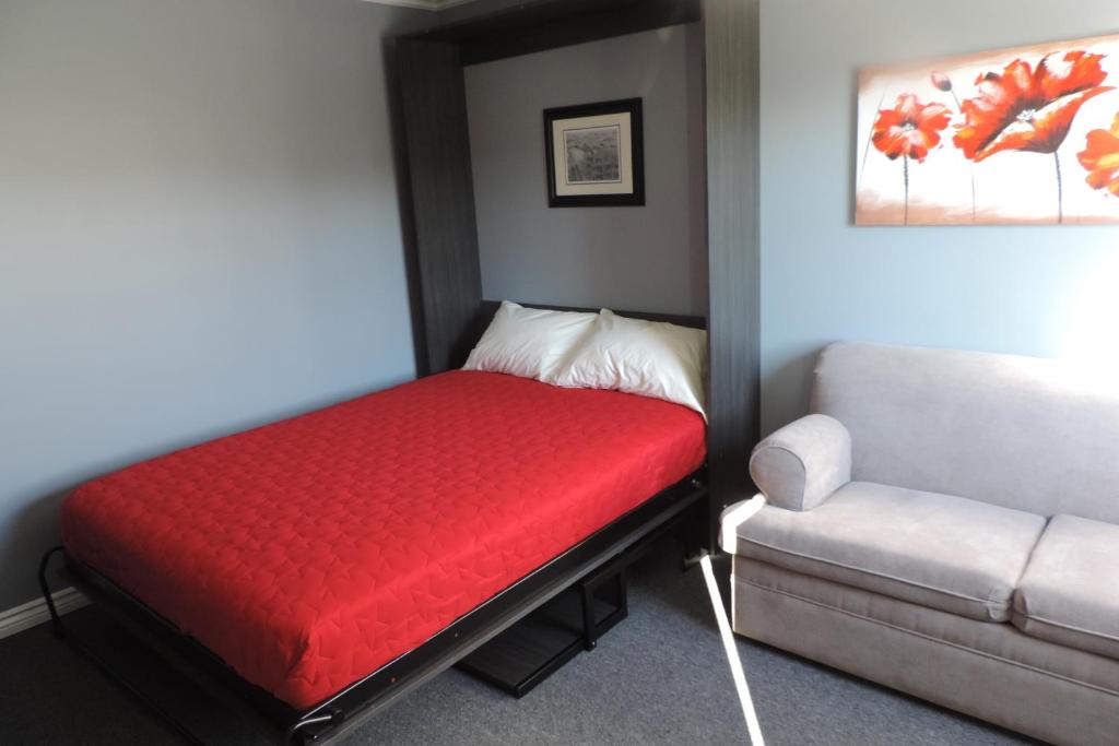 a small room with a red bed and a couch at North 99 Motel in Twillingate