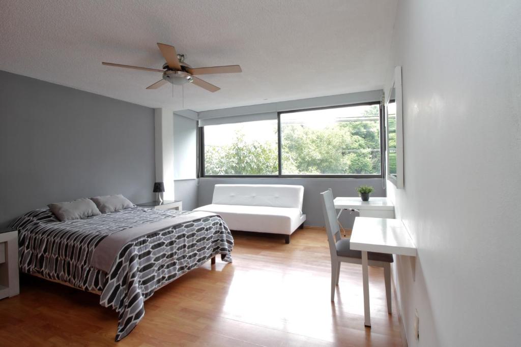 a bedroom with a bed and a couch and a window at Suite G Mancera in Mexico City