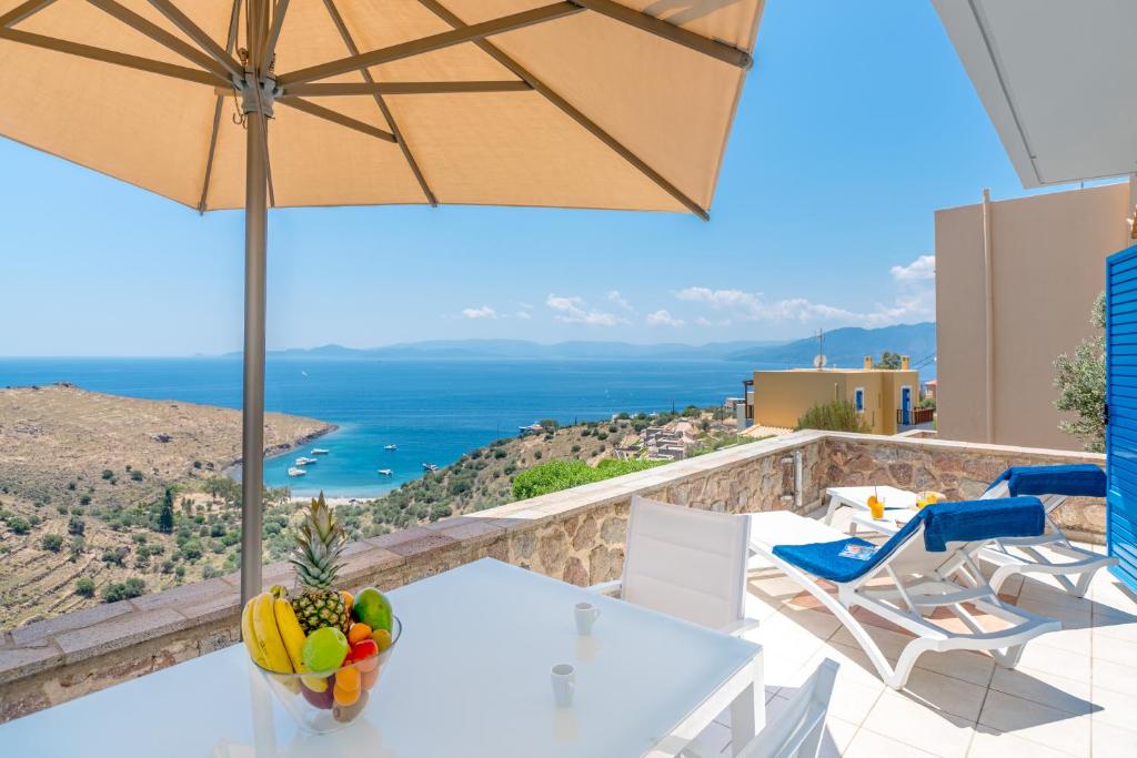 a balcony with a table and chairs and an umbrella at Thea Villas Aegina in Perdhika