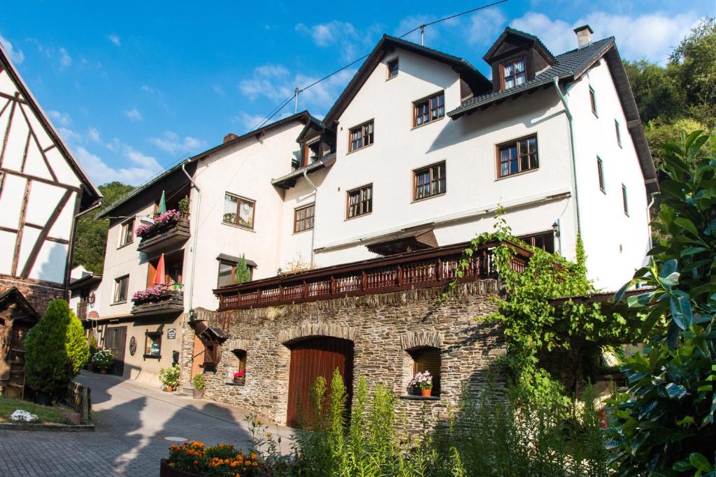 a large white building on a stone wall at Ferienwohnungen Lithos in Oberwesel