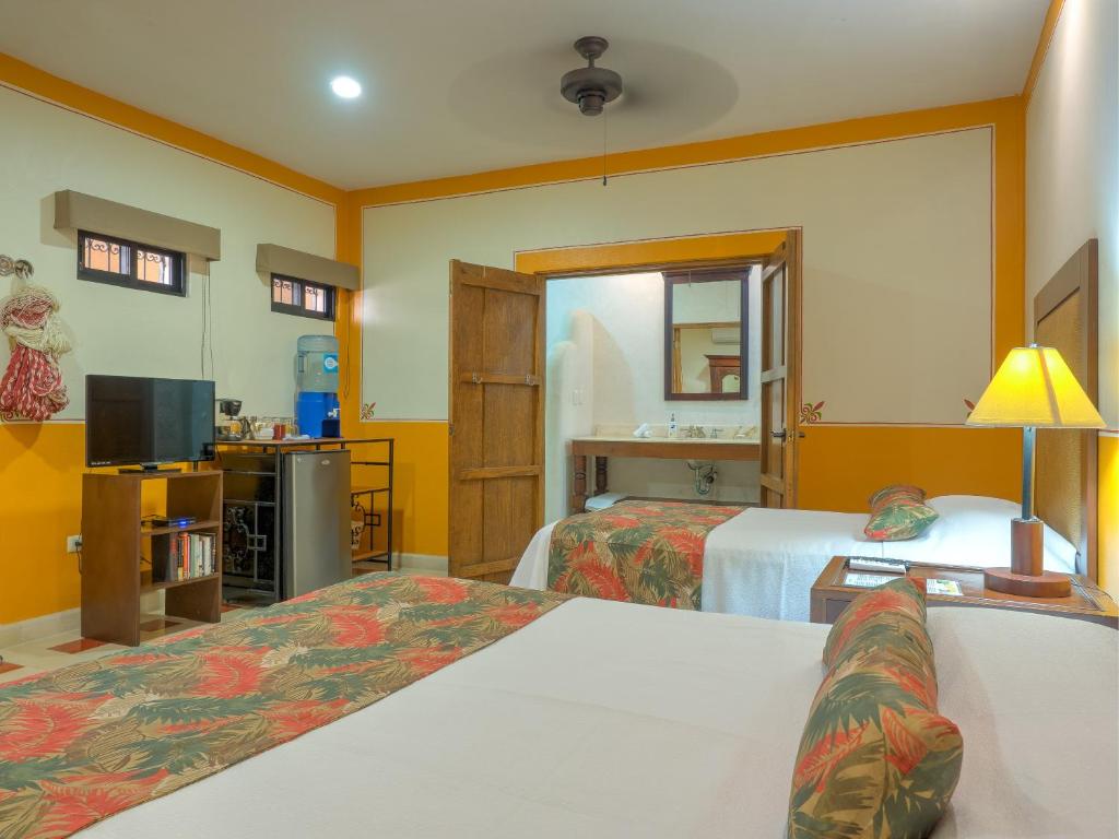 a hotel room with two beds and a television at Hotel Luz en Yucatan in M&eacute;rida