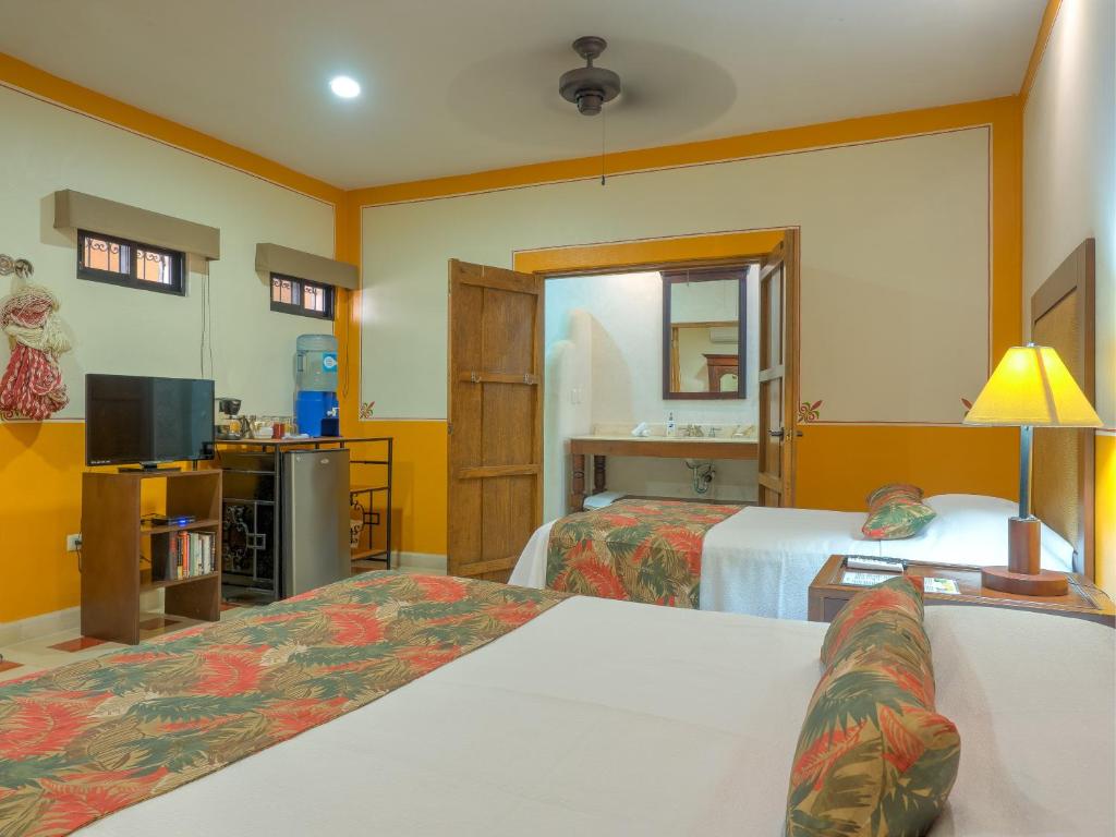 a hotel room with two beds and a television at Hotel Luz en Yucatan in Mérida