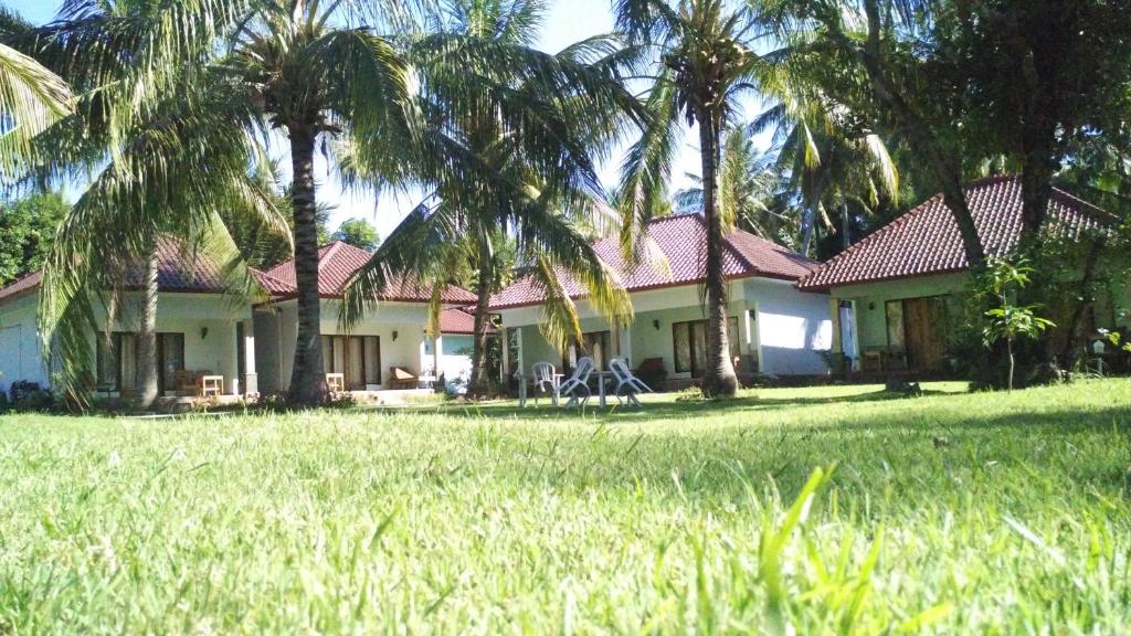 een huis met palmbomen voor een tuin bij Pondok Siola in Labuhanpandan