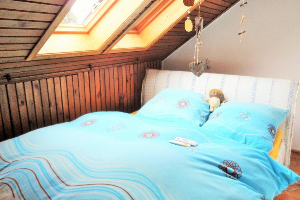 Una cama con sábanas azules y un osito de peluche. en Ferienwohnung-Kuechler en Oelsnitz