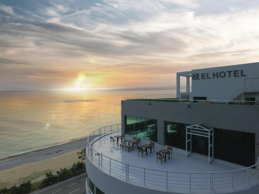 um edifício com mesas e cadeiras na praia em EL Hotel em Yangyang