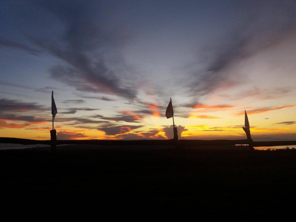 una puesta de sol con dos banderas en la playa en Overview Hostel en Loon