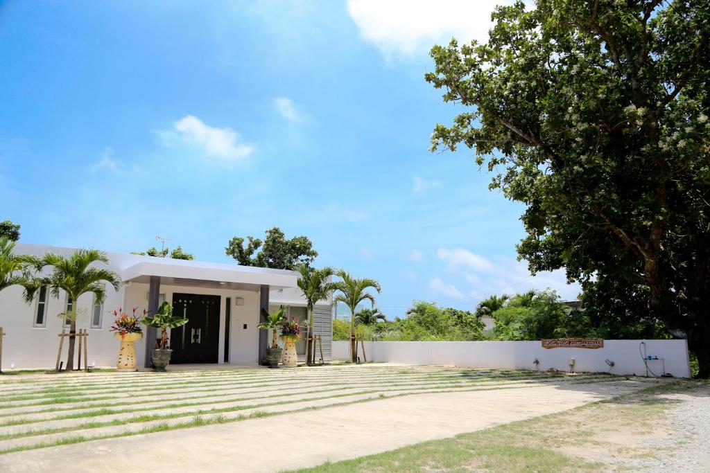 un edificio blanco con un árbol delante en Palm Villa Ishigakijima igusa, en Ishigaki Island