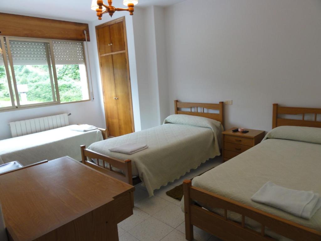 Habitación pequeña con 2 camas y mesa. en Pensión Monterredondo en Meira