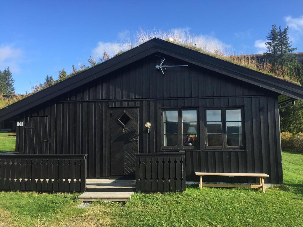 a black cottage with a bench in front of it at Skei Apartments in Svingvoll