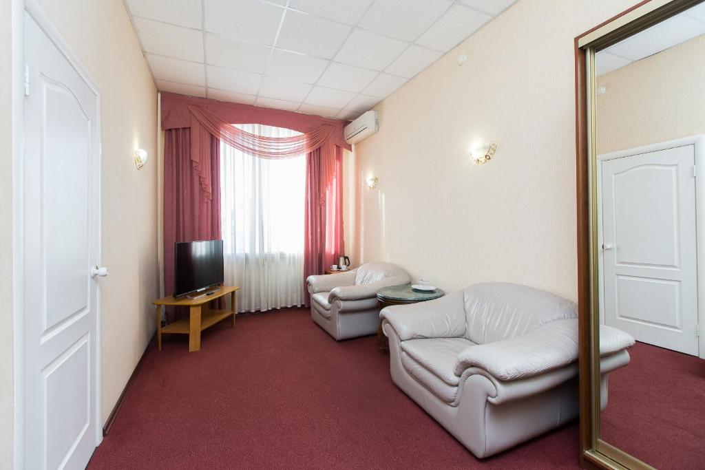 車里雅賓斯克的住宿－Gostiny Dom Vizit，客厅配有两把椅子和镜子