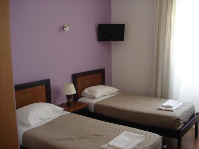 a bedroom with two beds and a tv on the wall at Areia Da Foz in Figueira da Foz