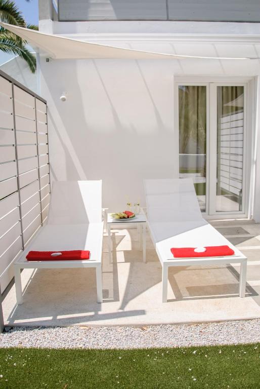 two white benches sitting on a patio at Kouros Seasight Hotel in Pythagoreio