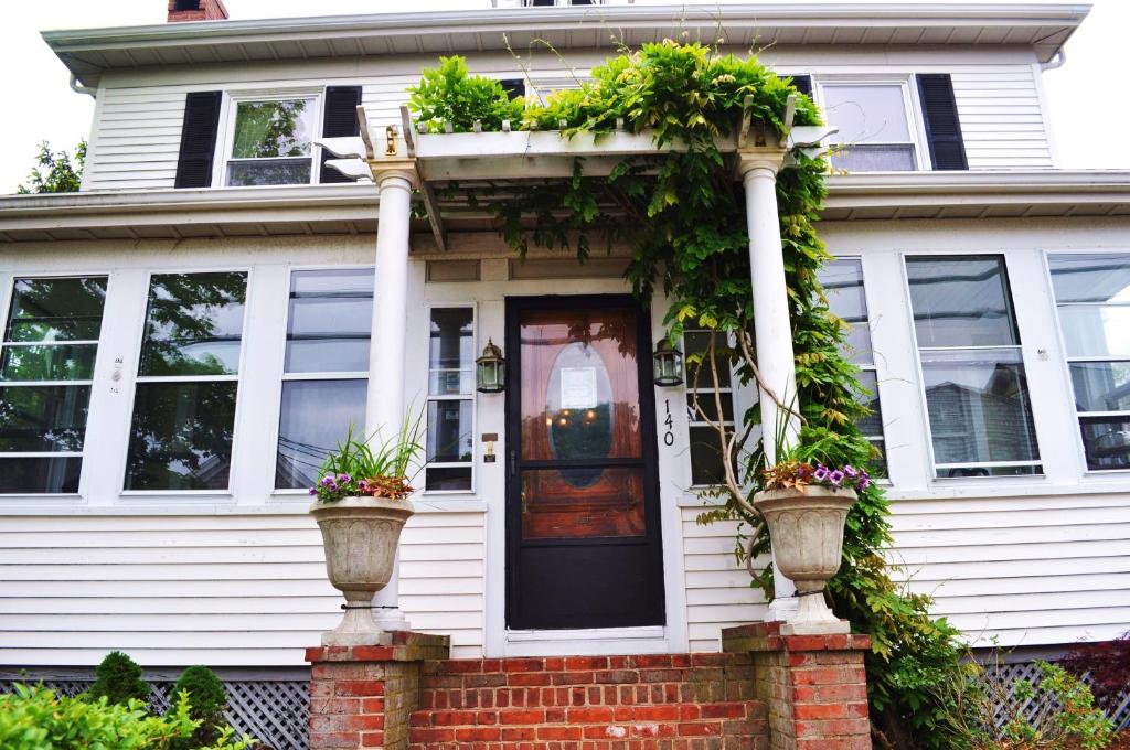 une maison blanche avec des plantes en pot sur la porte d'entrée dans l'établissement The John Randall House, à Provincetown