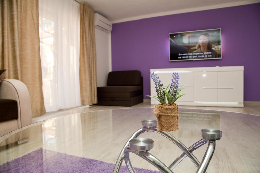 een woonkamer met paarse muren en een glazen tafel bij Deluxe Apartment Nika in Kaštela