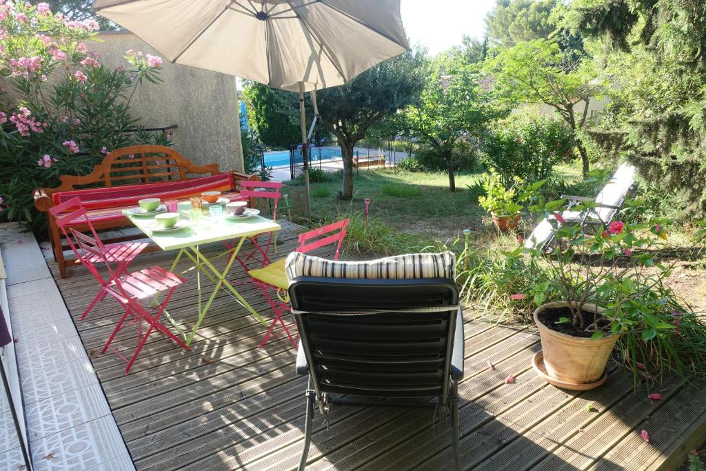 un patio con mesa, sillas y sombrilla en Gîte du Fenouil, en Lézignan-Corbières