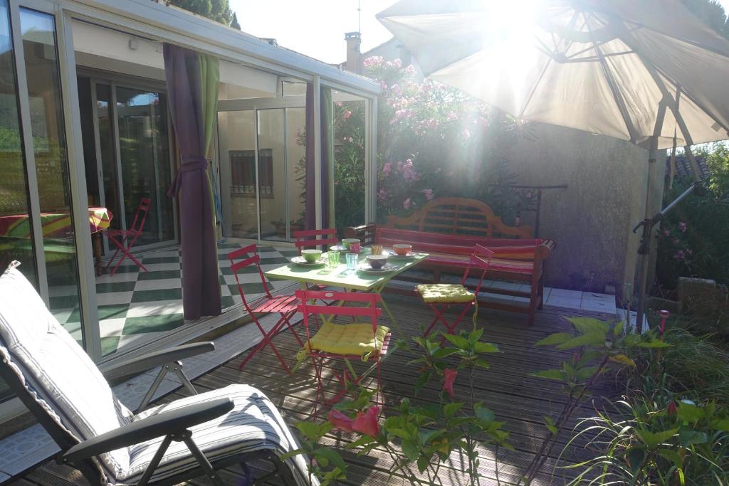 un patio con mesa, sillas y sombrilla en Gîte du Fenouil, en Lézignan-Corbières