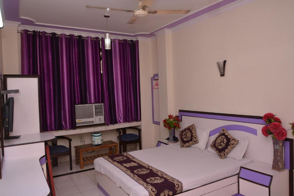 1 dormitorio con 1 cama con cortinas moradas y TV en Hotel Yatri International, en Nueva Delhi
