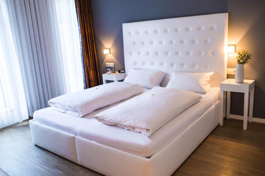 Una cama blanca con dos almohadas encima. en Hotel Domizil en Ingolstadt